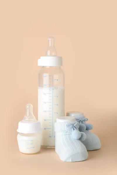 Bottles Milk Baby Booties Pale Orange Background — Stock Photo, Image