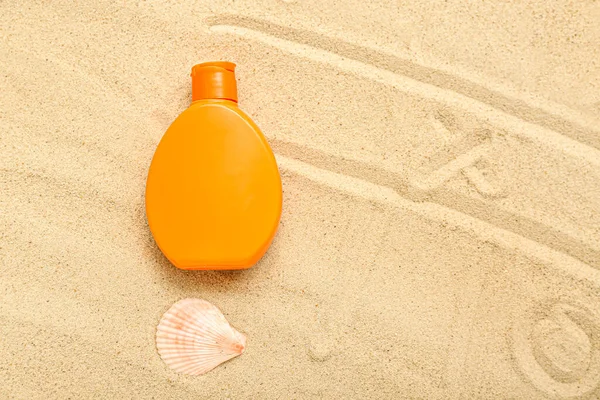 Creative composition with bottle of sunscreen cream and seashell on sand