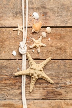Kahverengi ahşap arka planda ipli deniz kabukları ve deniz yıldızları