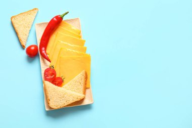 Lezzetli işlenmiş peynir tabağı. Mavi arka planda ekmek ve sebzeler.
