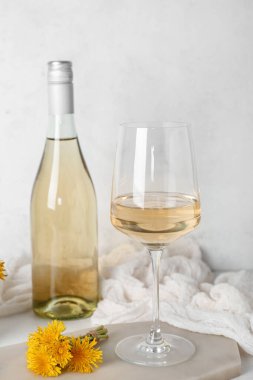 Beyaz masada bir şişe ve bir bardak karahindiba şarabı.