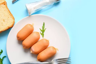 Lezzetli kaynamış sosis tabağı ve mavi arka planda roka.