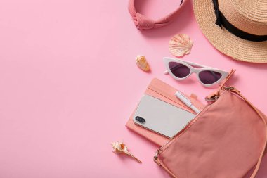 Cep telefonlu şık çanta ve pembe arka planda farklı aksesuarlar.