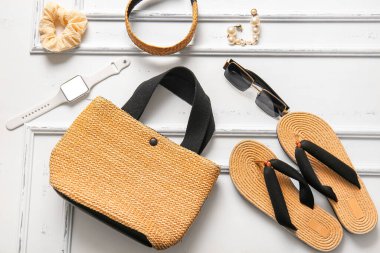 Saati olan şık bir çanta ve beyaz arka planda farklı aksesuarlar.