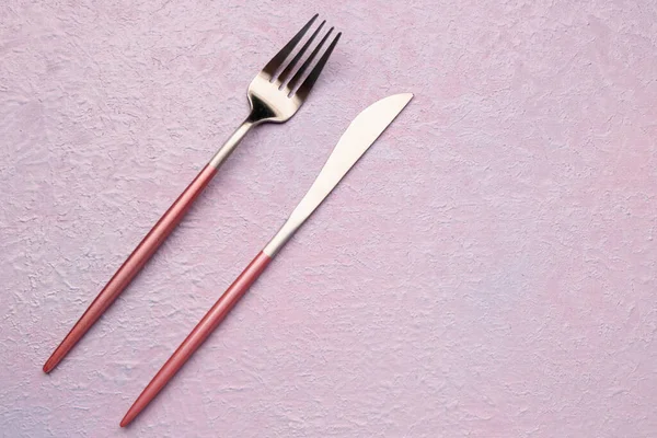 淡いピンクの背景にステンレス製のフォークとナイフ — ストック写真