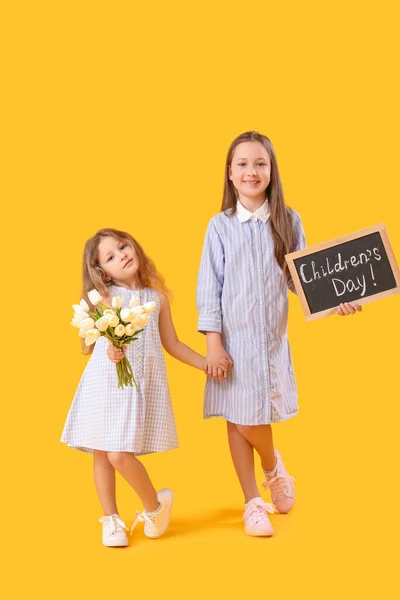 小さな女の子開催Chalkboardともにテキスト子供の日とチューリップ上の黄色の背景 — ストック写真