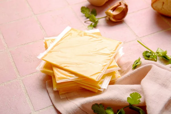 stock image Slices of tasty processed cheese with herbs on pink tile background