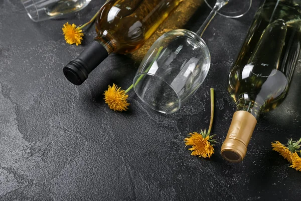 Bottles and glass of dandelion wine on black background