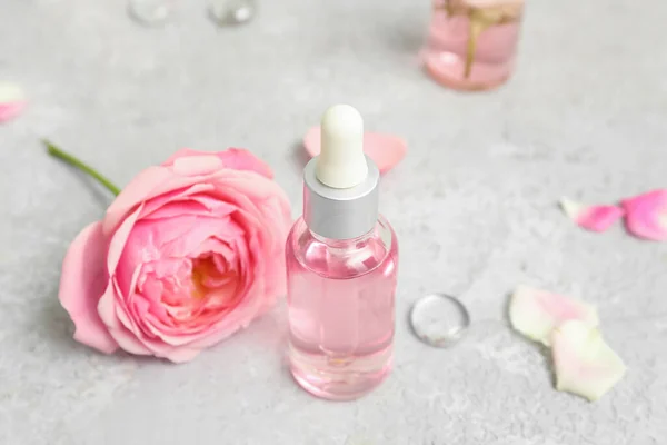 Gül Özü Beyaz Masa Üzerinde Çiçekler Olan Kozmetik Yağı Şişeleri — Stok fotoğraf