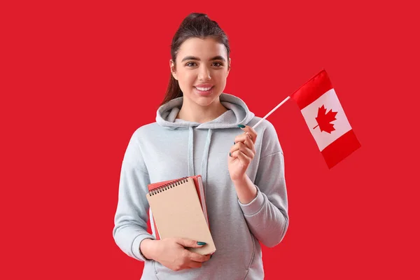 拿着加拿大国旗和红色背景书籍的年轻女子 — 图库照片