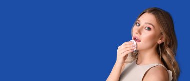 Güzel genç bir kadın mavi arkaplanı makyajla temizliyor.