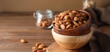 Ahşap masada lezzetli bademlerle dolu bir kase, yakın plan.