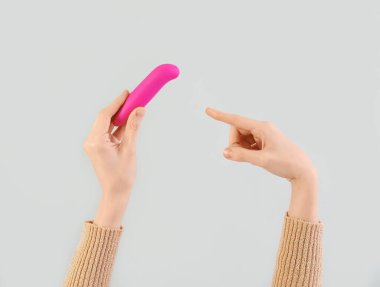 Kadın arka planda pembe vibratöre bakıyor.