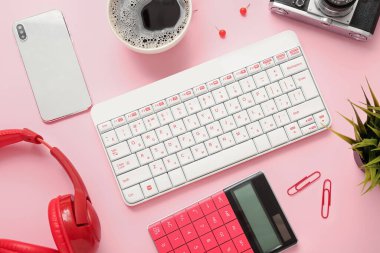 Pembe arka planda klavye, cep telefonu, kulaklık ve hesap makinesi ile kompozisyon