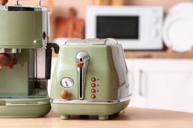 Modern kahve makinesi ve ekmek kızartma makinesi mutfaktaki ahşap masada.