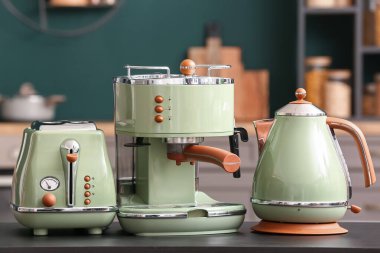 Elektrik ısıtıcısı, kahve makinesi ve tost makinesi mutfakta siyah masada.