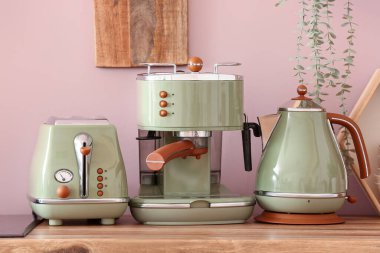 Elektrik ısıtıcısı, tost makinesi ve kahve makinesi ahşap mutfak tezgahında.