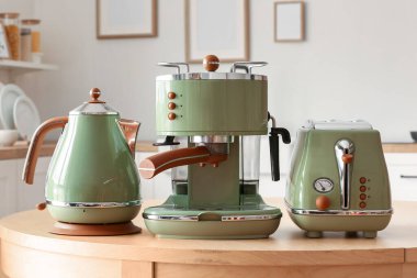 Elektrik ısıtıcısı, tost makinesi ve kahve makinesi mutfaktaki ahşap masada.