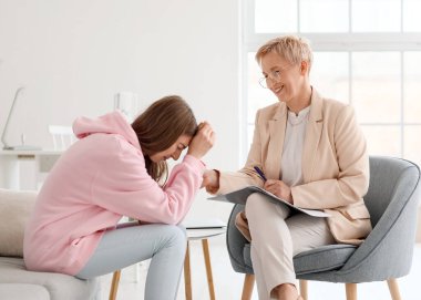 Ofiste ağlayan bir hastayla çalışan olgun bir psikolog.