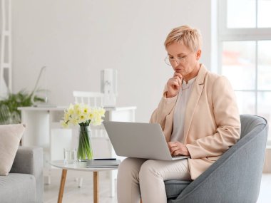 Ofiste dizüstü bilgisayarla çalışan düşünceli bir psikolog.