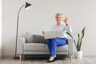 Diz üstü bilgisayarı olan olgun psikolog ofiste iyi olduğunu gösteriyor.