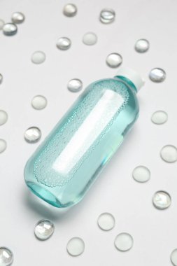 Hafif zemin üzerinde cam taşlar olan bir şişe mikiler suyu, yakın plan.