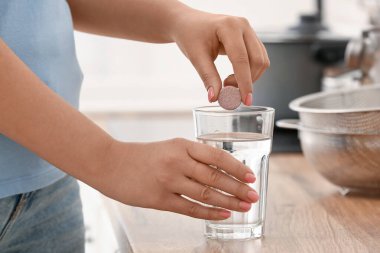 Mutfak tezgahındaki suya coşkulu tablet koyan kadın, yakın plan.