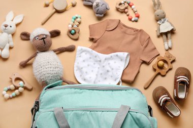 Bej arka planda bebek kıyafetleri ve oyuncakları olan kompozisyon
