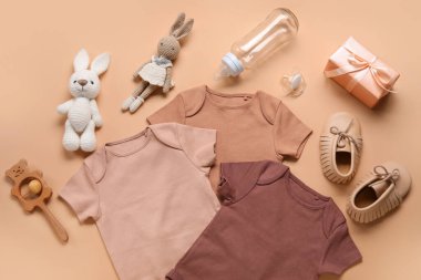 Bej arka planda bebek kıyafetleri, oyuncaklar ve aksesuarlarla kompozisyon