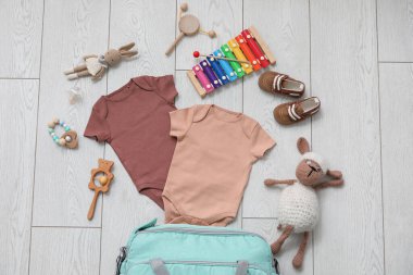 Hafif ahşap arka planda bebek için şık kıyafetler ve oyuncaklar