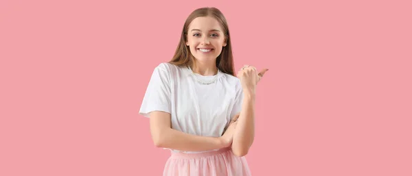 Ευτυχισμένη Νεαρή Γυναίκα Μπλουζάκι Που Δείχνει Κάτι Ροζ Φόντο — Φωτογραφία Αρχείου