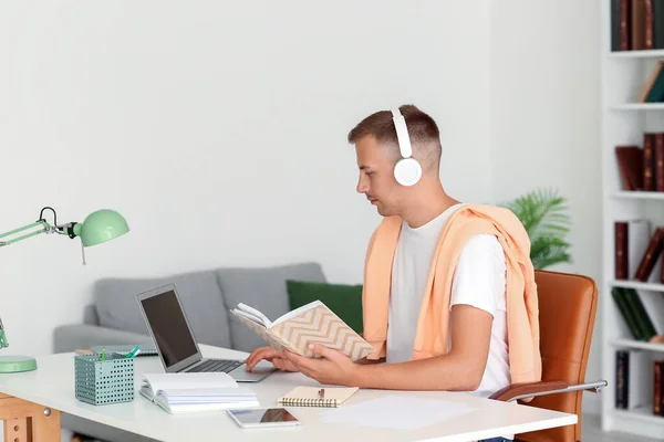 Νεαρός Άνδρας Ακουστικά Βιβλίο Και Laptop Μελετώντας Online Στο Σπίτι — Φωτογραφία Αρχείου