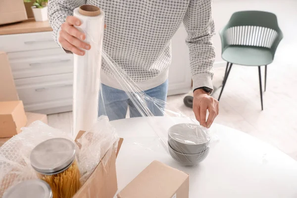 Genç adam kaseleri streç filmle kaplıyor, mutfakta, yakın plan.