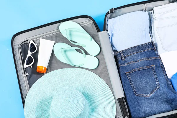 青い背景にビーチアクセサリー付きオープンスーツケース — ストック写真