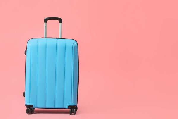 Blue suitcase on pink background