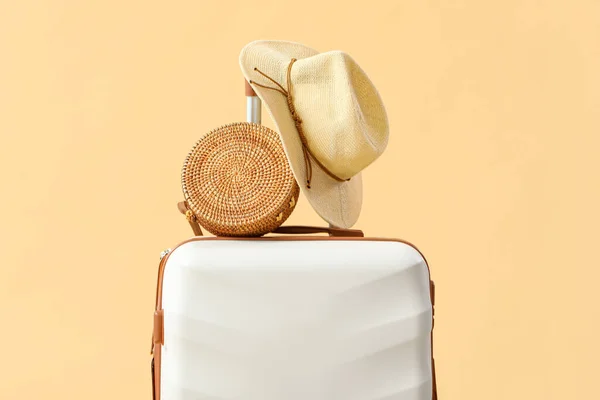 Suitcase with summer hat and bag on beige background