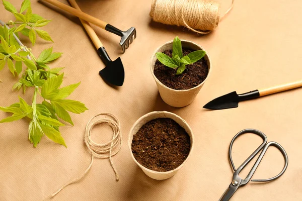 Bej arka planda fide ve bahçıvanlık araçları olan turba kapları