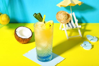 Mavi duvarın yanındaki sarı masada limon ve çiçekli taze yaz kokteyli.