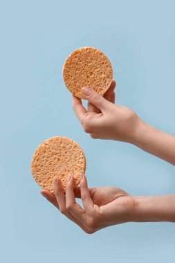 Açık mavi arkaplanda makyaj için süngerli eller