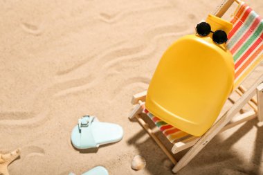 Kum üzerinde güneş kremi ve plaj aksesuarlarıyla yaratıcı kompozisyon