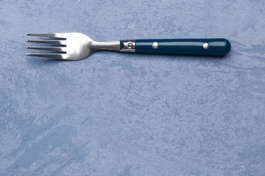 Paslanmaz çelik çatal, arka planda plastik sapı var.