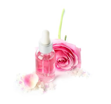 Beyaz arka planda gül özü ve çiçekli bir şişe kozmetik yağı.