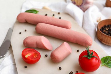 Beyaz arka planda fesleğenli ve domatesli lezzetli sosisler.