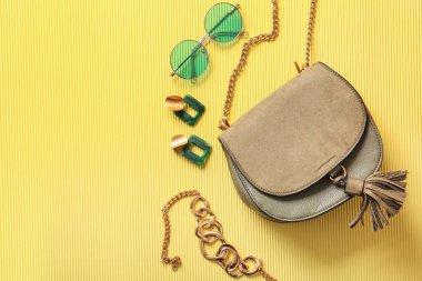 Şık çanta ve sarı arka planda farklı aksesuarlar.
