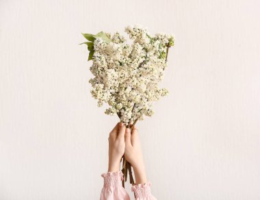 Beyaz arka planda bir buket leylak çiçekli kadın elleri