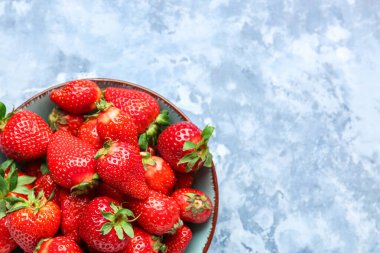 Mavi arka planda taze çilekli kase