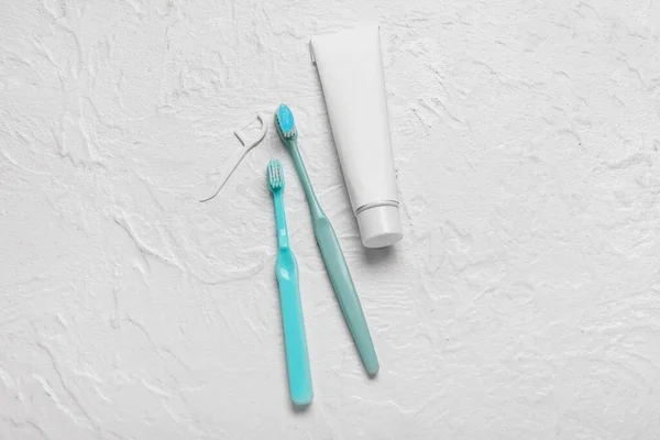 stock image Toothbrushes with paste and toothpick on white textured background