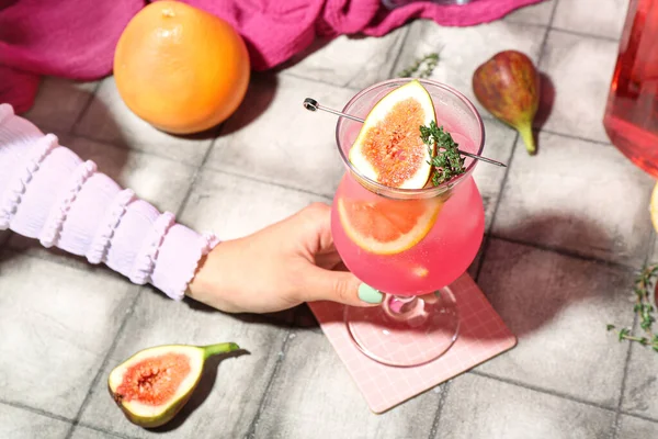 女人端着一杯夏天新鲜的鸡尾酒 桌上放着无花果 柚子和百里香 — 图库照片