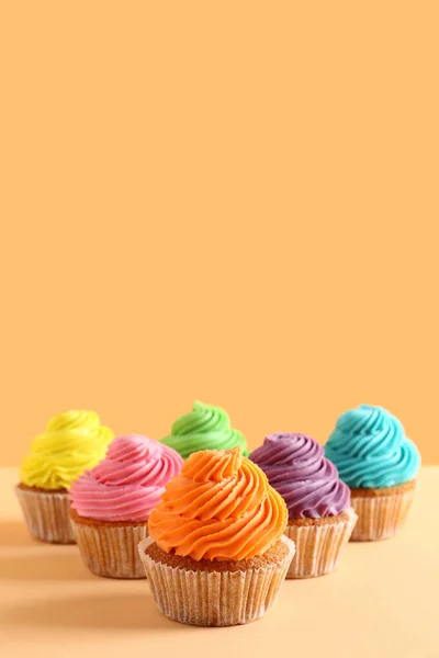 オレンジの背景においしいカラフルなカップケーキ — ストック写真