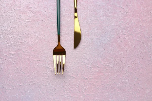 浅粉色背景的不锈钢叉子和刀片 — 图库照片